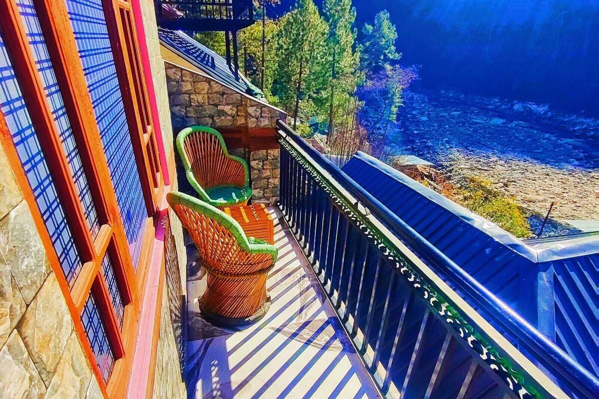 A balcony with a stone wall, a hammock, and wicker chairs.