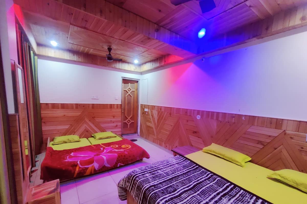 A room with wooden walls and ceiling, two beds with yellow and red bedding, a wooden door, and a ceiling fan.