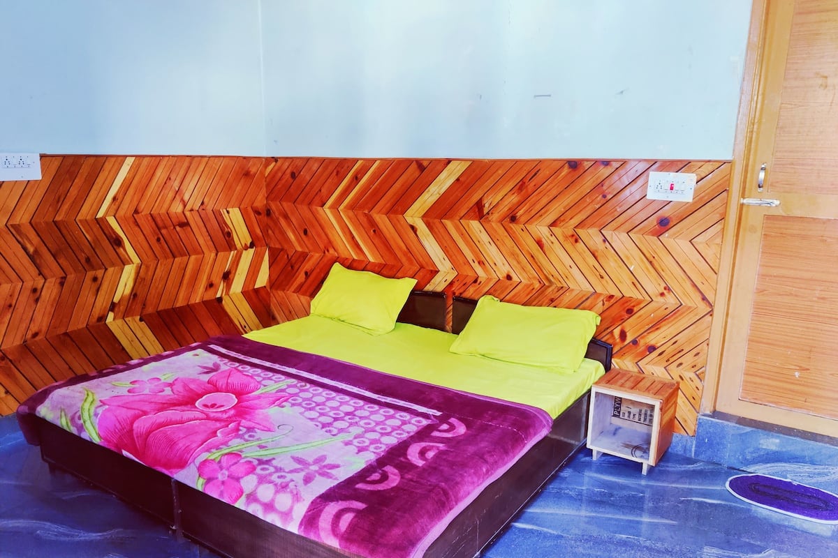 A room with a bed, a small wooden nightstand, and a wooden wall with a chevron pattern.