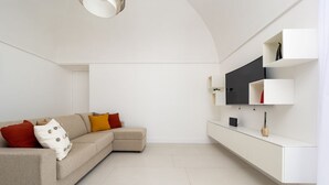 A modern living room with a sofa, a TV, and a white console table.