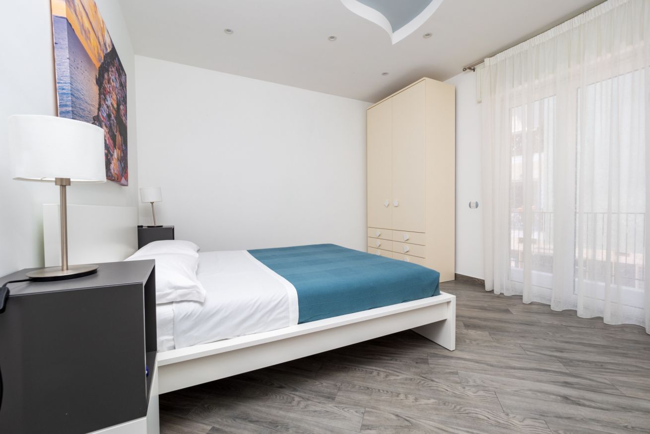 A modern bedroom with a bed, a desk, a wardrobe, and a window with curtains.