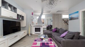 A modern living room with a flat-screen TV, a sofa, a coffee table, and a fireplace. - Partenope – Elegant Design Apartment in the Heart of Sorrento Coast (Piano di Sorrento)
