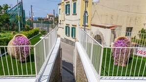 Una escalera con barandillas blancas que lleva a un edificio con contraventanas verdes.
