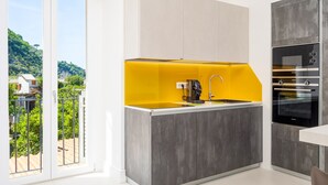 Una cocina moderna con una pared de acento amarilla, horno empotrado y vistas a un paisaje verde a través de una puerta corrediza.
