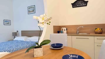 A hotel room with a bed, a small dining table with blue bowls, a potted orchid, and a sign on the wall.