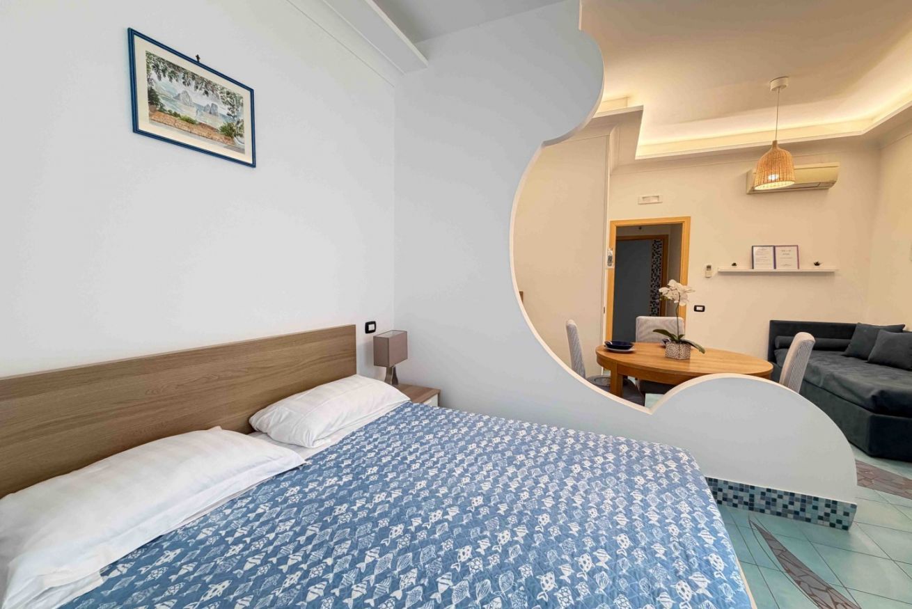 Ein Hotelzimmer mit Bett, Schreibtisch, Stuhl, Sofa und Esstisch.