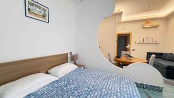 Ein Hotelzimmer mit Bett, Schreibtisch, Stuhl, Sofa und Esstisch.