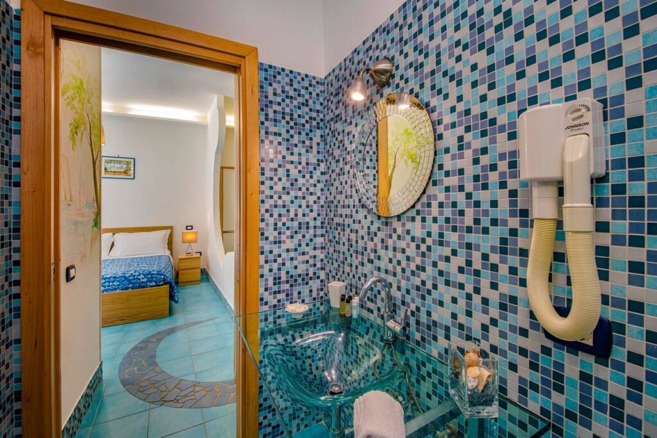 Ein Badezimmer mit einem Glaswaschbecken, einem Spiegel und einem Handtrockner.