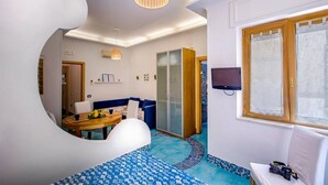 Una habitación con una cama, una mesa de comedor, un sofá, un televisor y una ventana.