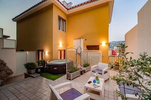 A patio with outdoor furniture, a hot tub, and a view of the city.