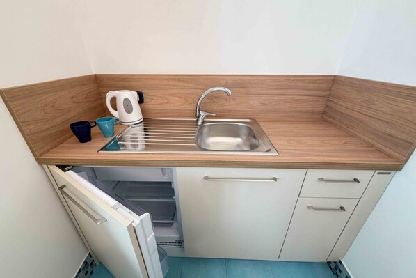 Eine kompakte Küche mit Holz Arbeitsplatte, Spüle aus Edelstahl und einem integrierten Geschirrspüler.