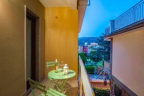 A balcony with a table, chairs, a bottle, and a lantern.