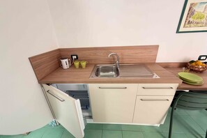 Une petite cuisine équipée comprenant un évier, un petit placard et un plan de travail.