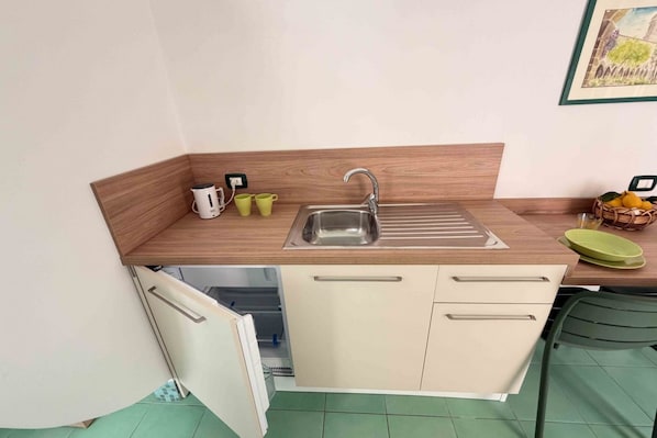 A compact kitchenette with a sink, a small cabinet, and a countertop.