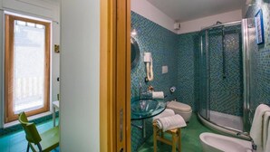 Un baño con lavamanos de vidrio, inodoro y ducha.