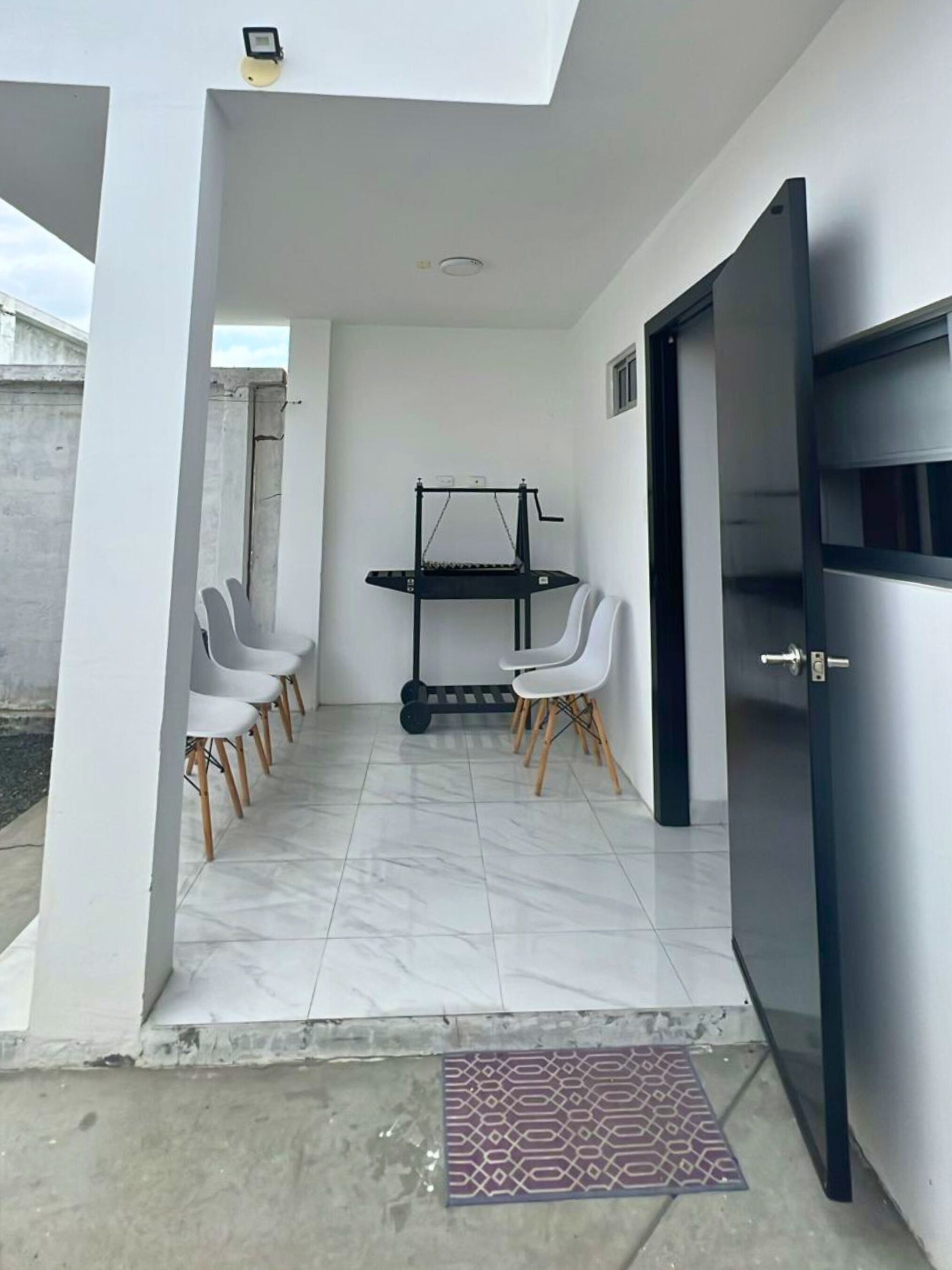 Una stanza moderna con una porta nera, un tavolino con sedie e una lampada a soffitto.