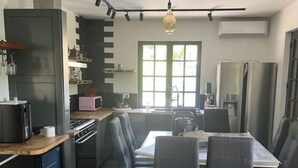A modern kitchen with dark cabinetry, a dining table, and chairs. - House Vezac (Vezac)