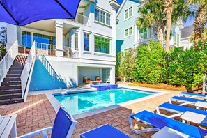 A pool area with blue-tiled pool, lounge chairs, and a staircase leading to a balcony. - Oceanfront Estate - Pool, Hot Tub, Pool Table, Bonus Boat- Exclusive Location (Hilton Head Island)