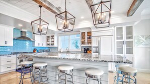 A modern kitchen with a large island, bar stools, and pendant lighting. - Oceanfront Estate - Pool, Hot Tub, Pool Table, Bonus Boat- Exclusive Location (Hilton Head Island)