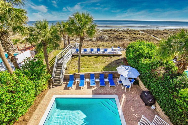 A pool area with blue lounge chairs, a small pool, and a view of the beach. - Oceanfront Estate - Pool, Hot Tub, Pool Table, Bonus Boat- Exclusive Location (Hilton Head Island)