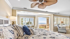 A bedroom with a large bed, a desk, and a view of the ocean. - Oceanfront Estate - Pool, Hot Tub, Pool Table, Bonus Boat- Exclusive Location (Hilton Head Island)