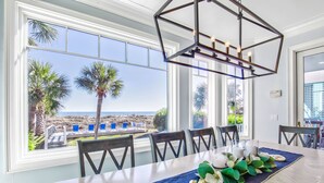 A dining area with a view of the beach, a table set with plates, candles, and a decorative leaf garland. - Oceanfront Estate - Pool, Hot Tub, Pool Table, Bonus Boat- Exclusive Location (Hilton Head Island)