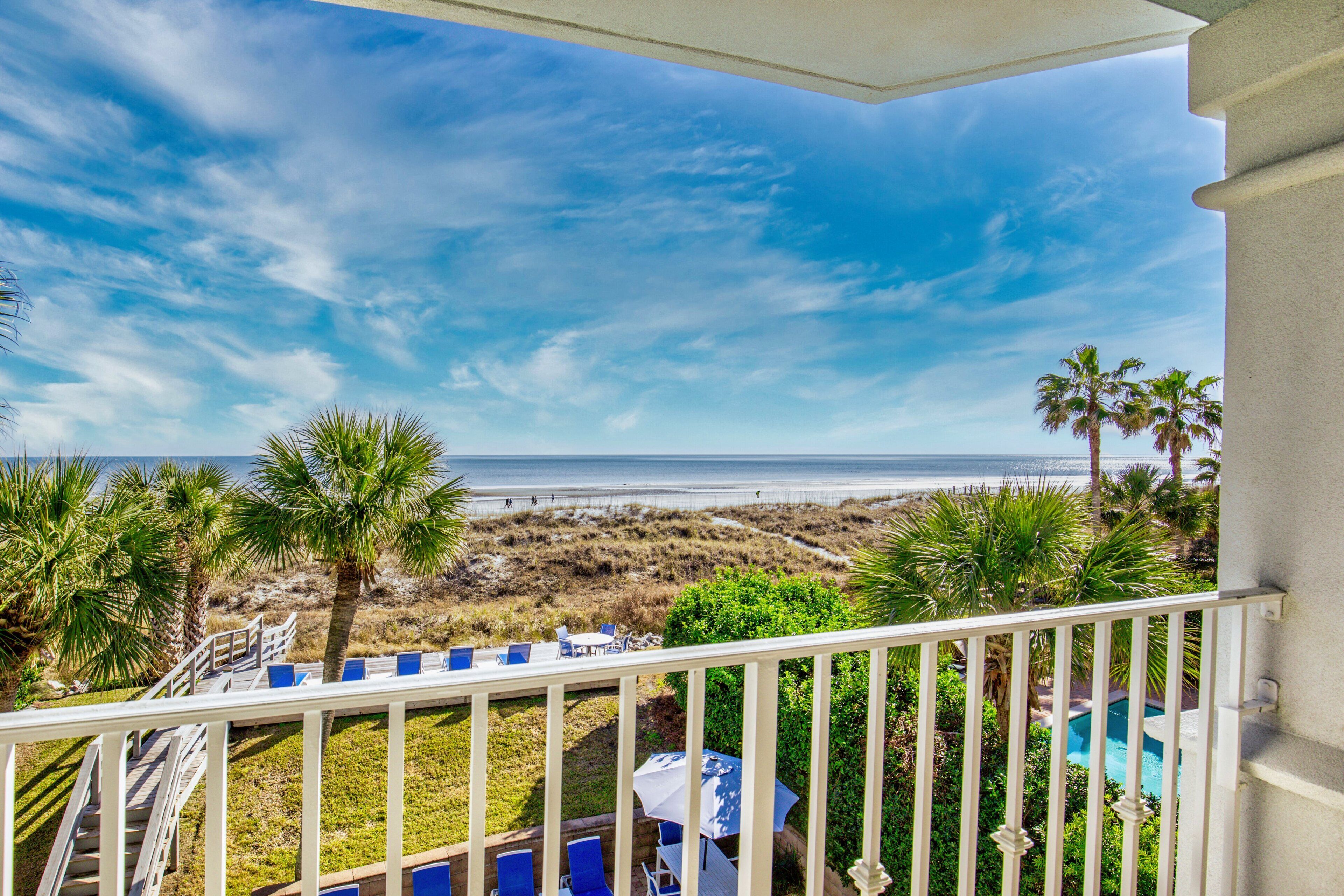 A balcony with a view of the beach and ocean.