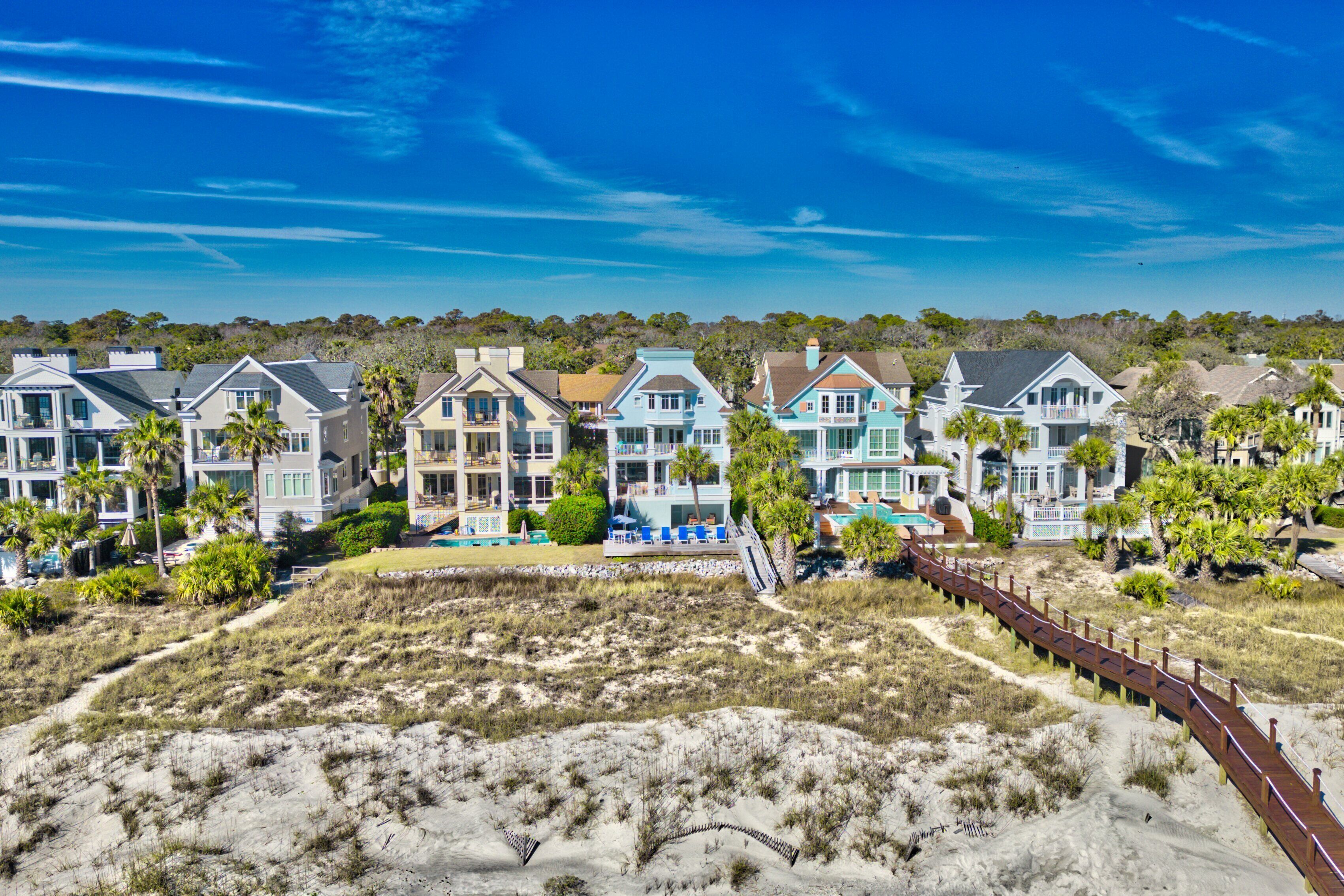 Une propriété située en bord de mer, comprenant plusieurs maisons, une plage de sable et une promenade en bois.