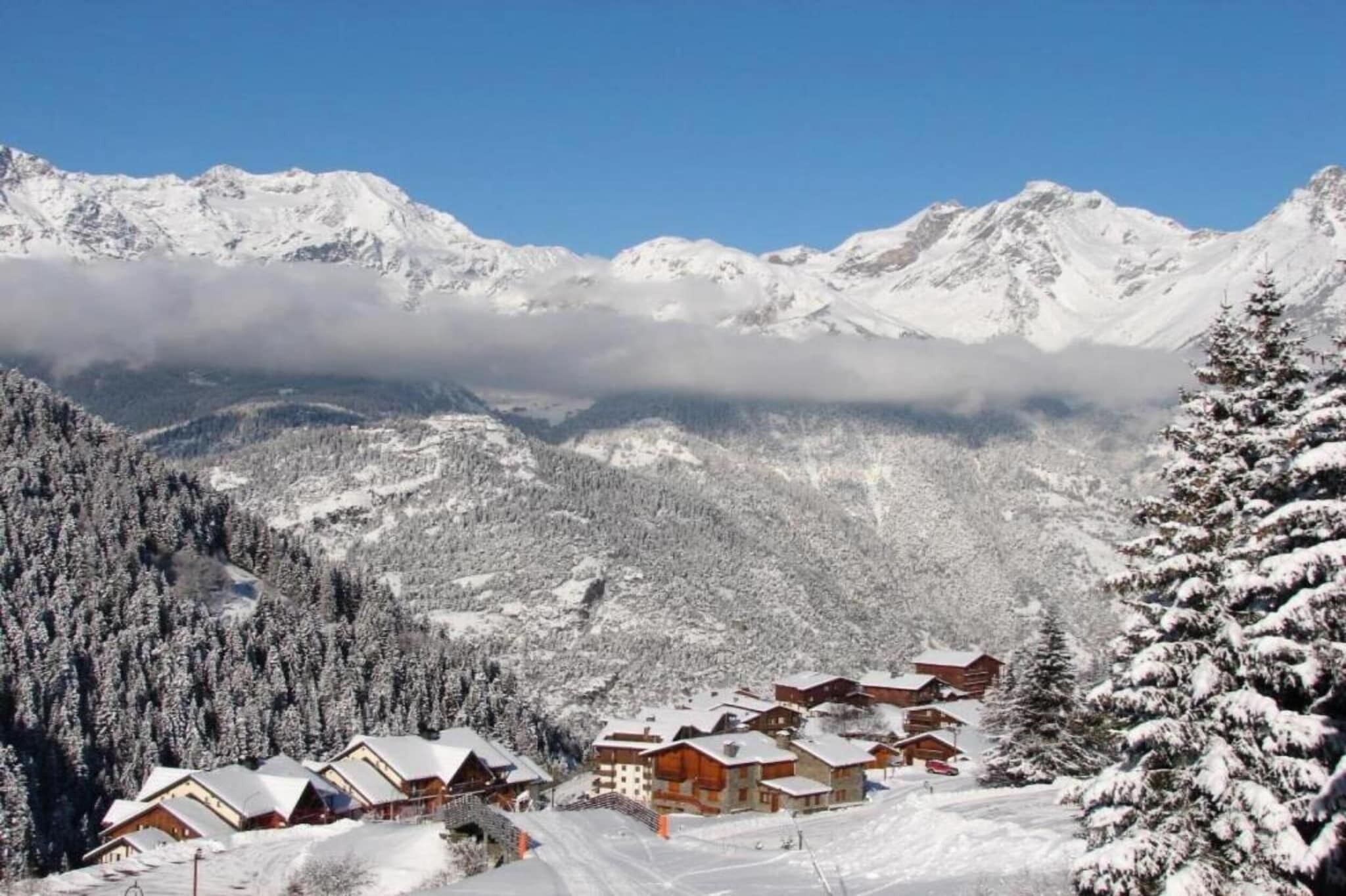 A snow-covered mountain village with wooden chalets and a ski slope.