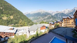 A mountain resort with wooden buildings, a pool, and a view of the surrounding mountains.