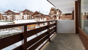 Un balcon offrant une vue sur un paysage enneigé et sur plusieurs bâtiments de style chalet.