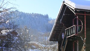 Un bâtiment en bois, avec un toit enneigé et un balcon.