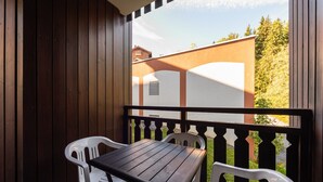 A balcony with a wooden table and white plastic chairs. - Apartment in Morillon at Ski Slope (Morillon)