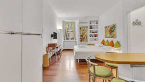 A modern hotel room with a bed, a desk, and a dining area. - Naviglio 13 - Welcomely (Milan)