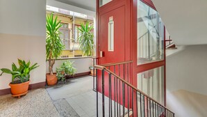 A red door with a glass panel, potted plants, and a tiled floor. - Naviglio 13 - Welcomely (Milan)