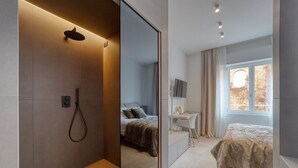 Un dormitorio moderno con una cama grande, un escritorio y una zona de ducha.