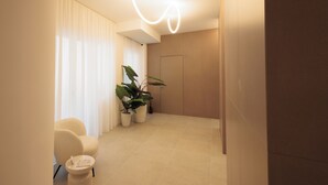 Habitación de hotel moderna con un diseño minimalista, que incluye una planta grande en maceta, un sillón cómodo y una pequeña mesa.