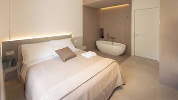 A modern bedroom with a large bed, a bedside table, a nightstand, a built-in bathtub, and a door.