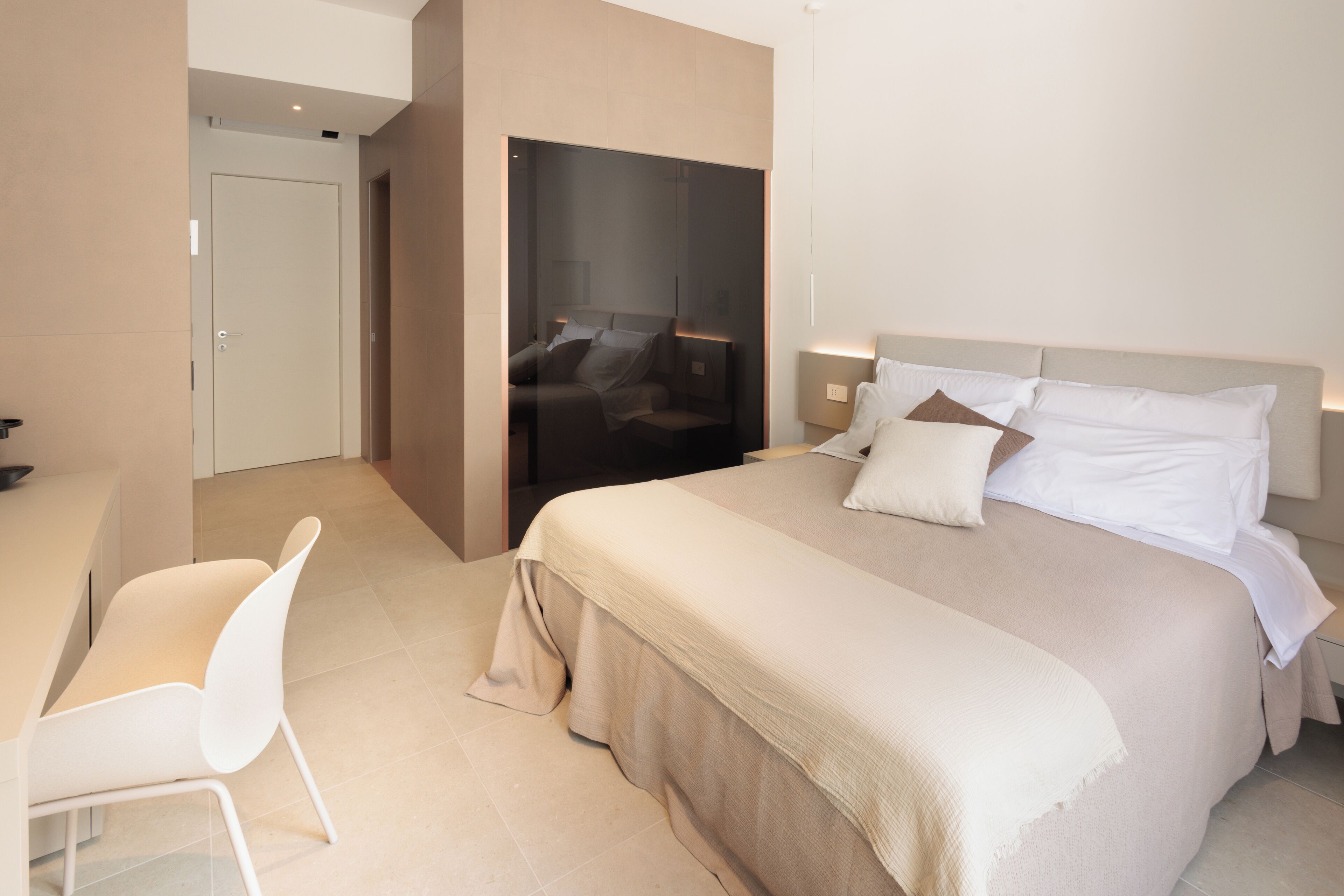 Ett modernt hotellrum med en stor säng, ett skrivbord och en stol.