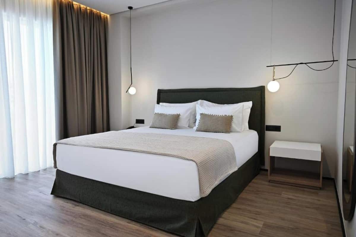 Ein modernes Hotelzimmer mit einem großen Bett, Nachttischen und Blick ins Freie.