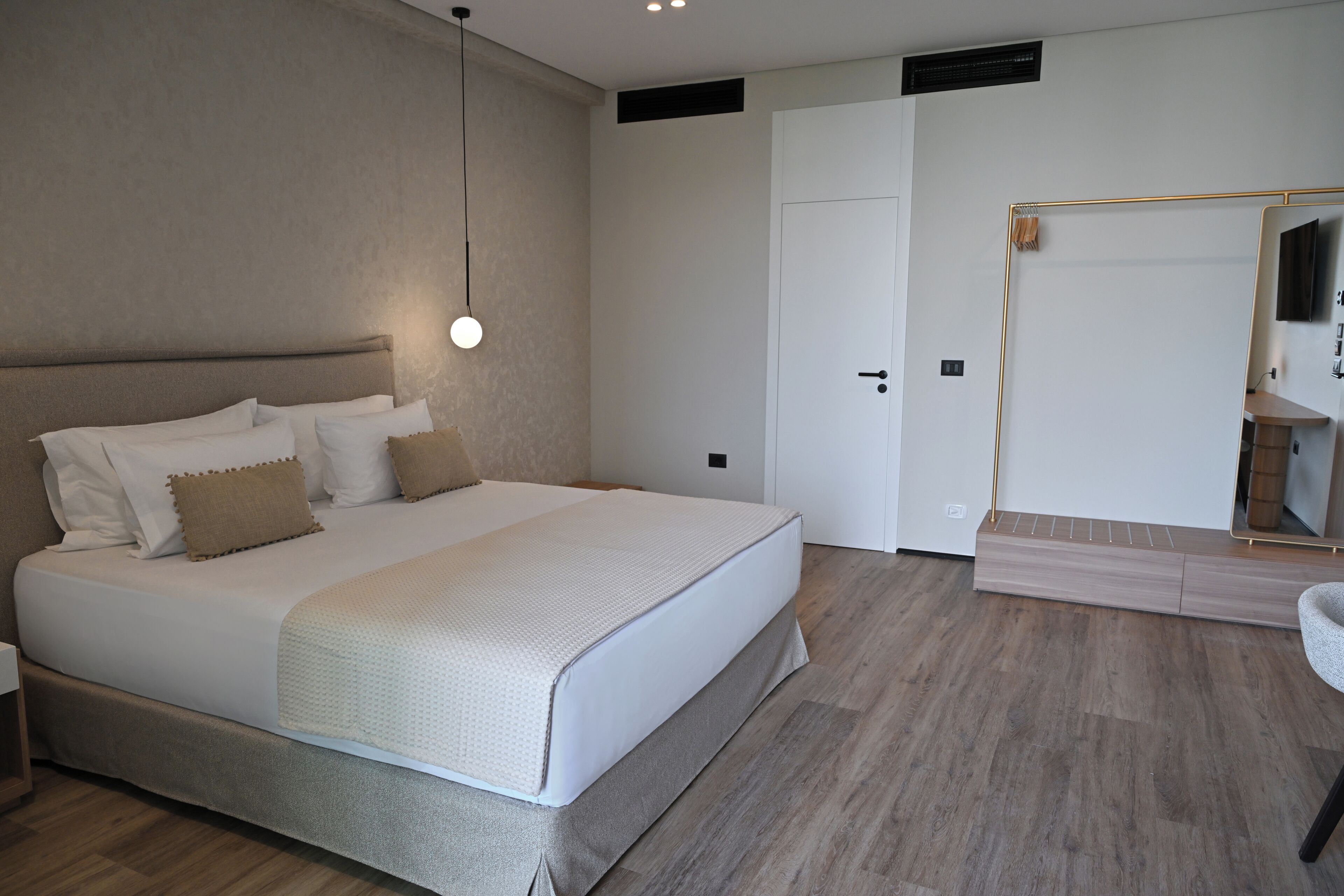 Un dormitorio con una cama grande, una mesita de noche, un espejo y una puerta.