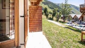 A wooden building with a balcony overlooking a parking area and a mountainous landscape. - Apartment in Saint-Sorlin near Ski Resort (Saint-Sorlin-d´Arves)