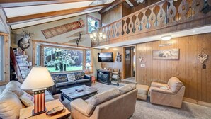 A cozy living room with a fireplace, leather sofas, a coffee table, and a television.