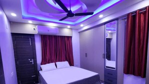A modern bedroom with a bed, ceiling fan, and red curtains. - Eastern Heights (Ranchi)