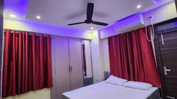 A modern bedroom with a bed, red curtains, a ceiling fan, and an air conditioning unit.