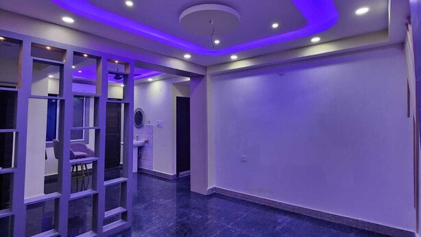 A spacious room with a dark marble floor, a glass partition with a chair, and a ceiling with recessed lighting. - Eastern Heights (Ranchi)