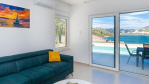 A modern living room with a green sofa, a yellow pillow, and a painting of a sailboat. - Luxury Villa Navis (Ploce)