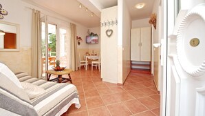 Un salon confortable avec un canapé, une table à manger et des chaises, un coin cuisine avec des placards et un téléviseur fixé au mur.