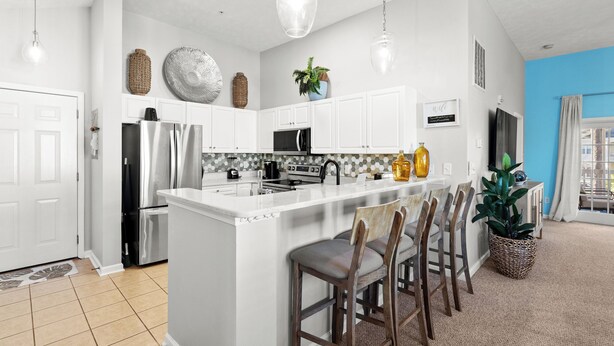 A modern kitchen with white cabinets, stainless steel appliances, and a central island with bar stools.
