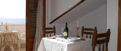 A dining area with a table set for two, a bottle of wine, and a candle on the table.